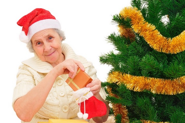 happy grandma in Santa cap decorating Christmas gifts